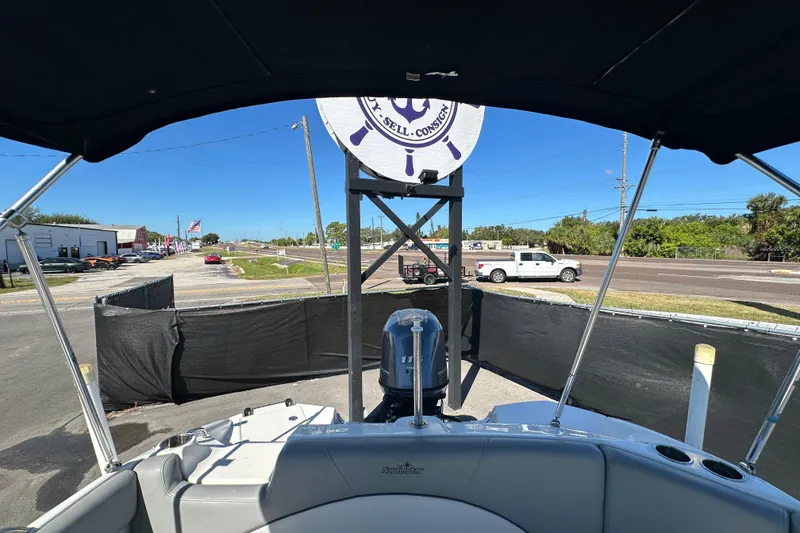 Slide: The Image of 2021 NauticStar 203 DC boat with canopy, parked near a road under clear blue sky. - 75
