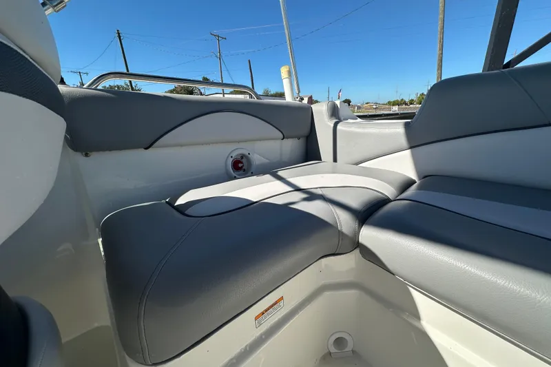 Slide: The Image of 2021 NauticStar 203 DC boat interior with gray cushioned seating under clear blue sky. - 79