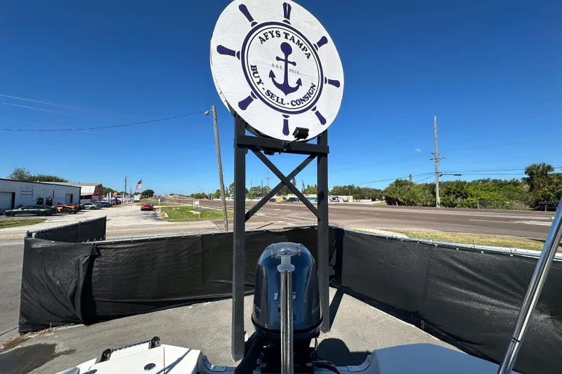 Slide: The Image of 2021 NauticStar 203 DC boat displayed at a dealership with a nautical-themed sign. - 87
