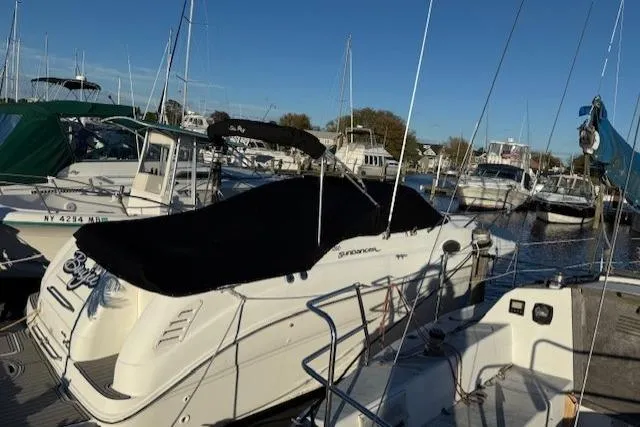 The Image of 1999 Sea Ray 260 Sundancer boat docked in a marina, covered with a black tarp. - 0