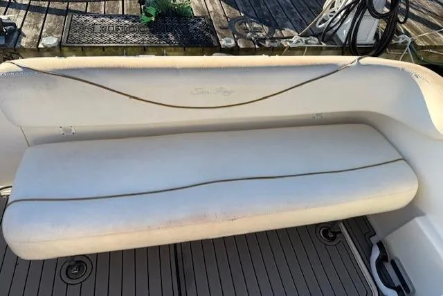 Slide: The Image of 1999 Sea Ray 260 Sundancer boat seating area with white cushioned bench. - 15