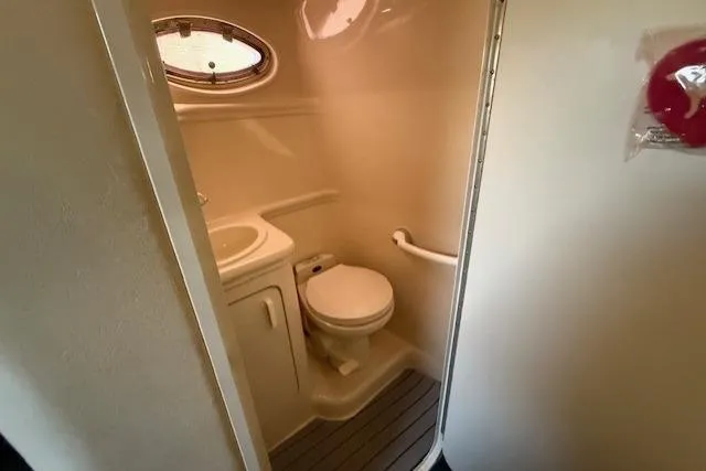 Slide: The Image of 1999 Sea Ray 260 Sundancer bathroom with sink, toilet, and porthole window. - 19