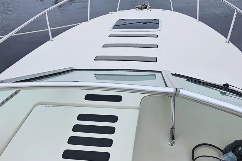 Slide: The Image of 1999 Sea Ray 260 Sundancer boat deck with railing and hatch, on calm water. - 7