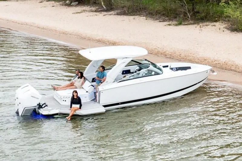 Slide: The Image of 2026 Four Winns H9 OB boat near sandy shore with people relaxing onboard. - 20