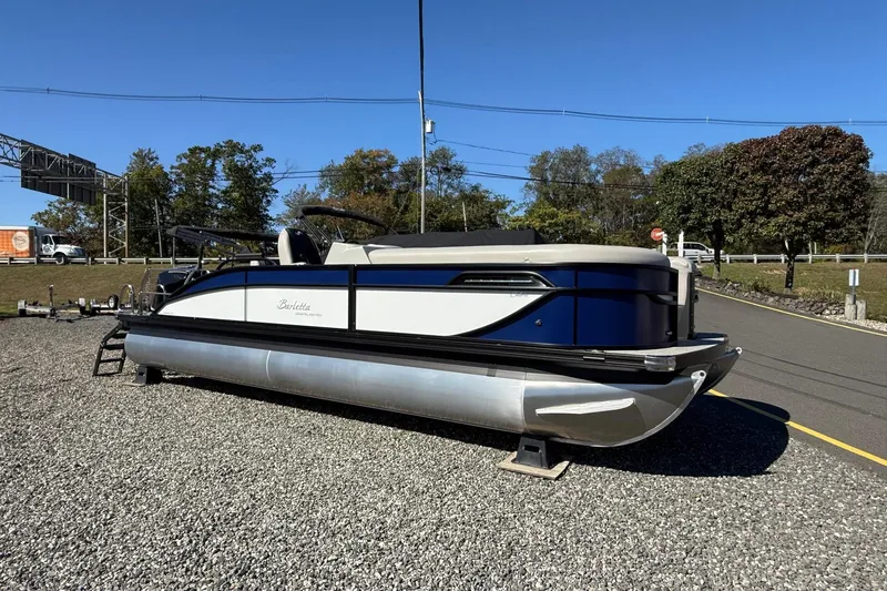 Slide: The Image of 2026 Barletta C24UC pontoon boat on gravel lot, clear sky background. - 1