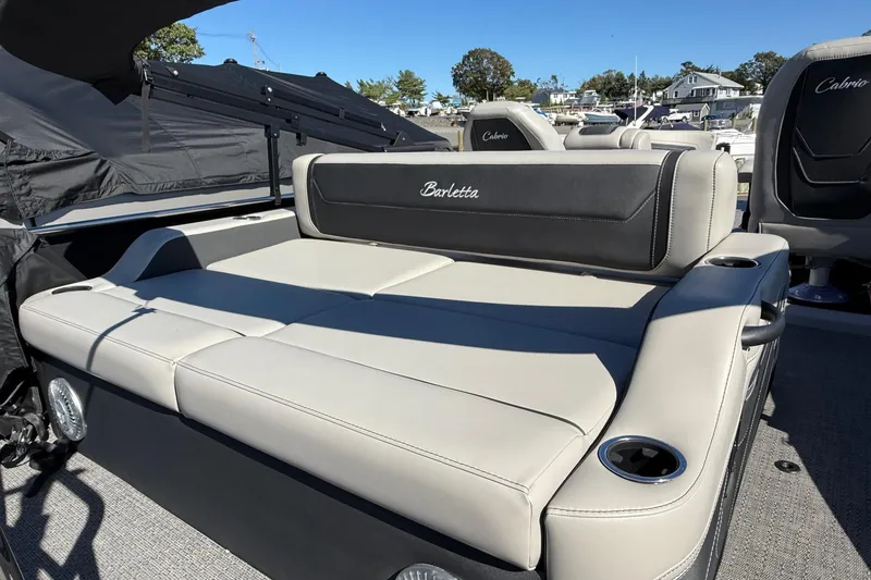 Slide: The Image of 2026 Barletta C24UC boat with luxurious seating and cup holders, docked under clear skies. - 14