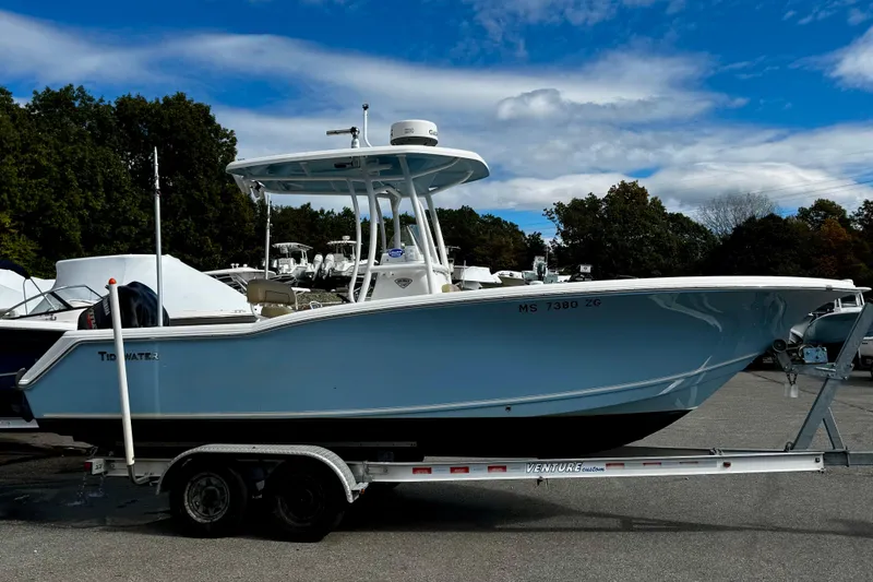 The Image of 2016 Tidewater 232 CC Adventure boat on trailer, surrounded by trees and other boats. - 0