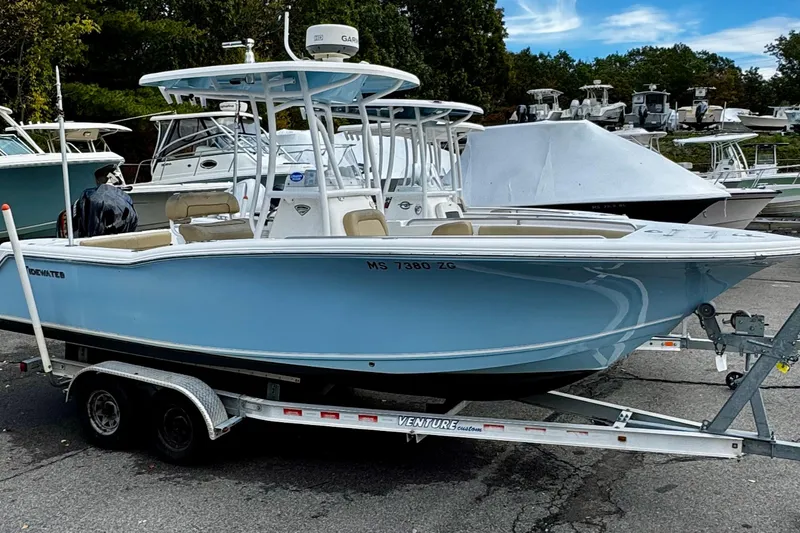 Slide: The Image of 2016 Tidewater 232 CC Adventure boat on trailer, parked outdoors under blue sky. - 2