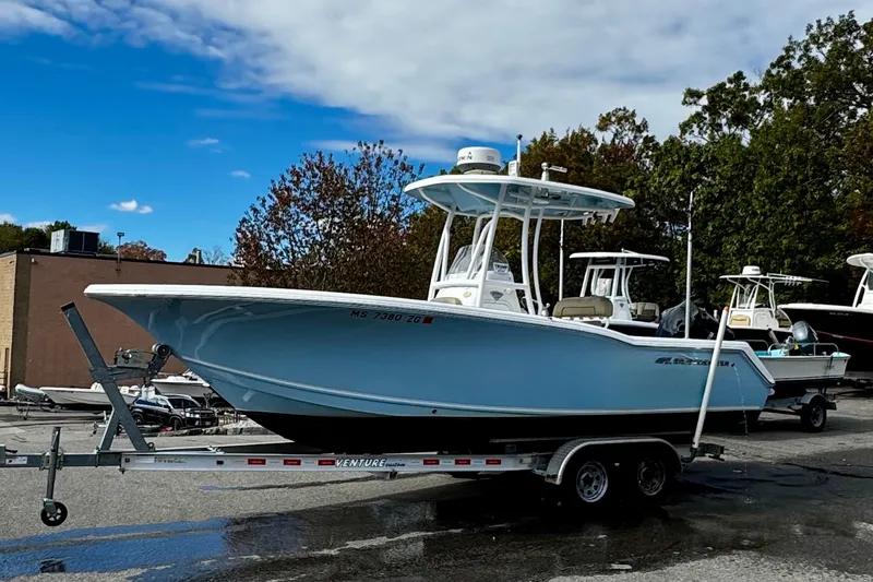 Slide: The Image of 2016 Tidewater 232 CC Adventure boat on trailer, parked outdoors under blue sky. - 4