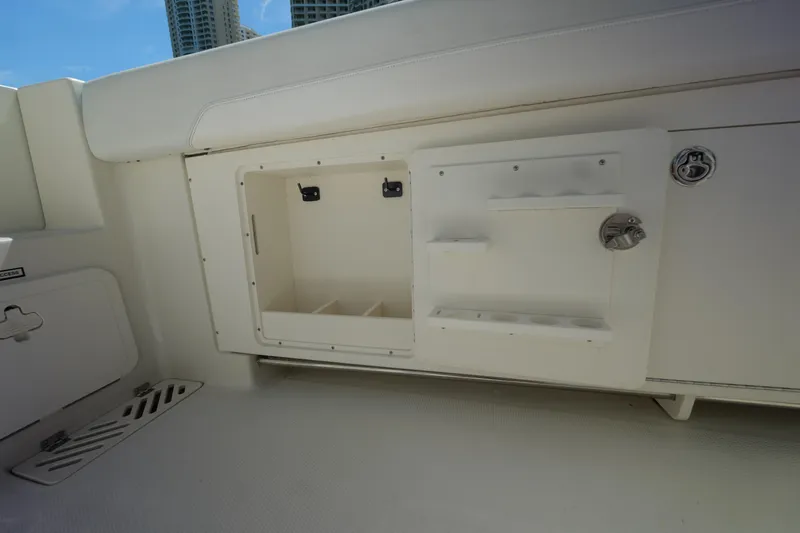 Slide: The Image of 2015 Sailfish 320 CC boat storage compartment with white interior and latch. - 23