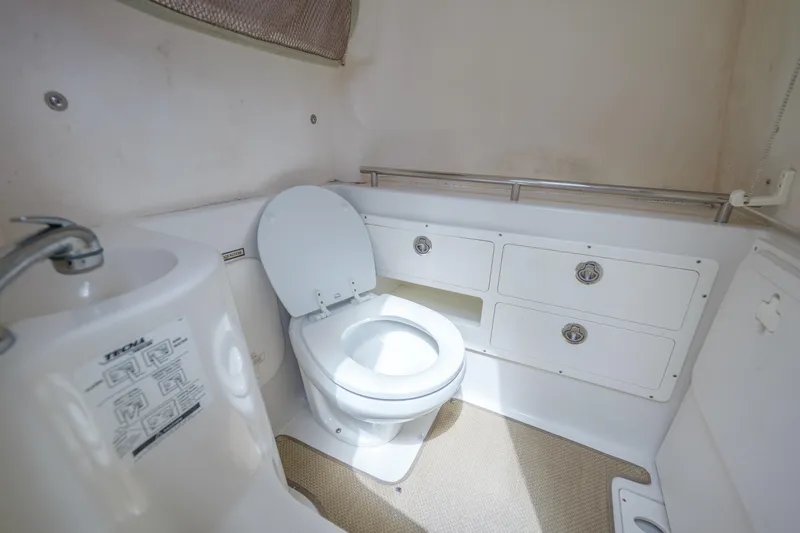 Slide: The Image of 2015 Sailfish 320 CC boat bathroom with toilet, sink, and storage cabinets. - 25