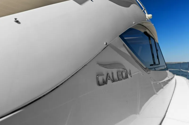 Slide: The Image of 2017 Galeon 385 HTS yacht with sleek design and logo, under clear blue sky. - 23