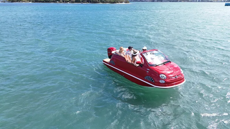 Slide: The Image of Red Car Off-shore Fiat 500 Classic boat on water, 2025 model, with passengers enjoying a ride. - 6