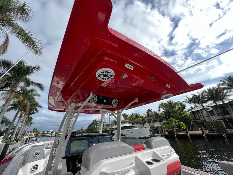 Slide: The Image of 2023 Fountain 38 SC boat with red canopy, docked near palm trees and waterfront homes. - 24