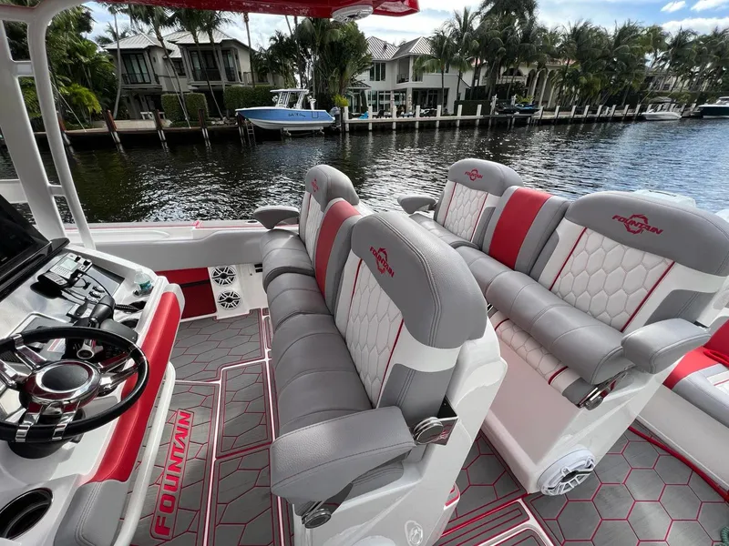 Slide: The Image of 2023 Fountain 38 SC boat interior with luxurious seating and modern steering, docked by waterfront homes. - 31