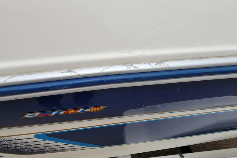 Slide: The Image of 1994 Sea Ray 180 Bow Rider with visible hull scratches and nautical flag decals. - 14
