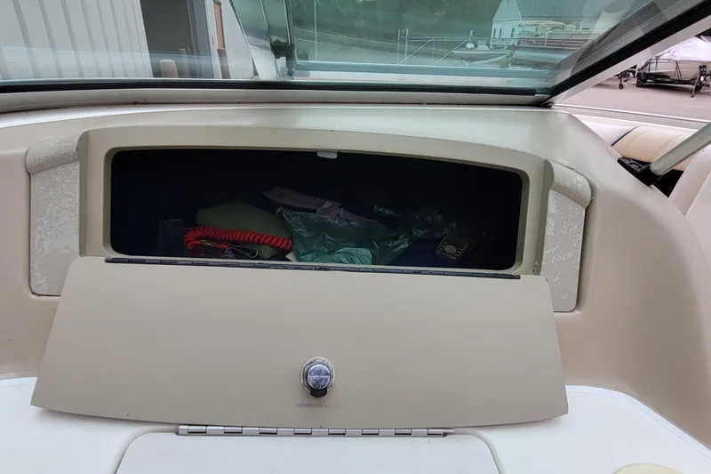 Slide: The Image of 1994 Sea Ray 180 Bow Rider glove compartment with open storage, showing various items. - 28