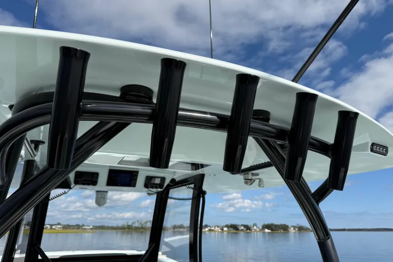 Slide: The Image of 2025 Front Runner 37 Catamaran with rod holders, clear sky, and calm water backdrop. - 21