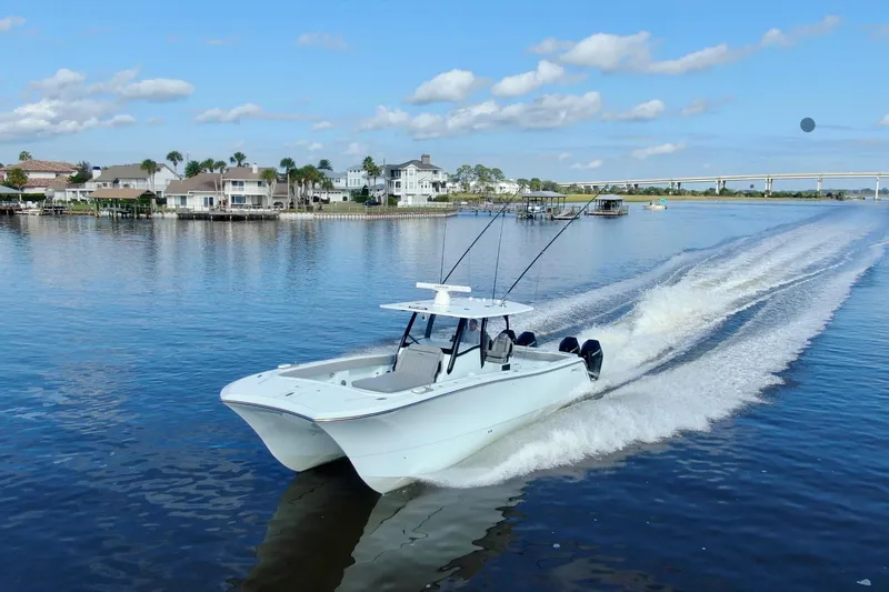 Slide: The Image of 2025 Front Runner 37 Catamaran cruising on a scenic waterway with waterfront homes. - 46