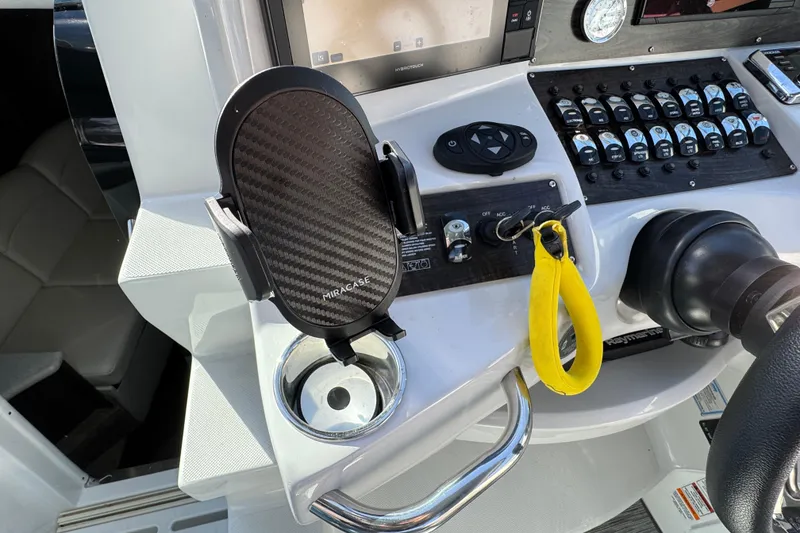 Slide: The Image of 2020 Rinker 320 EX helm with phone holder, controls, and yellow safety lanyard. - 10