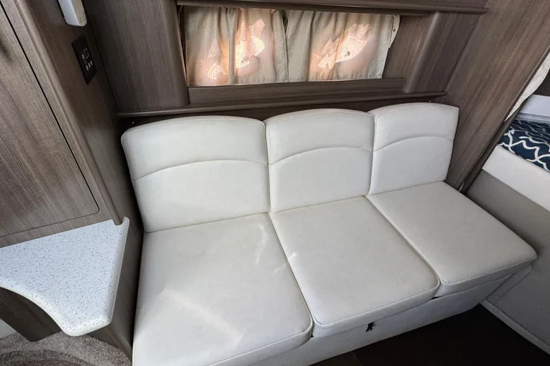 Slide: The Image of 2020 Rinker 320 EX interior with white leather sofa and wooden cabinetry. - 18