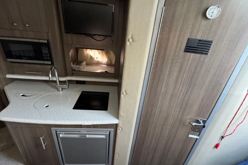 Slide: The Image of 2020 Rinker 320 EX boat interior with kitchenette, microwave, and modern design. - 23