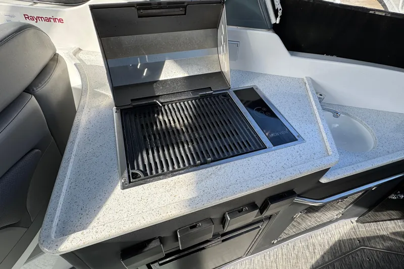 Slide: The Image of 2020 Rinker 320 EX boat kitchenette with grill and sink, featuring Raymarine equipment. - 6