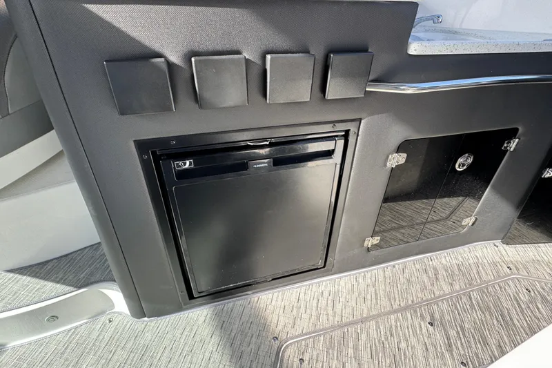 Slide: The Image of 2020 Rinker 320 EX boat interior with built-in mini fridge and storage compartments. - 7