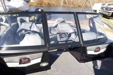 Slide: The Image of 2026 Ranger 2080MS boat interior with gray seating and windshield, docked by a lake. - 90