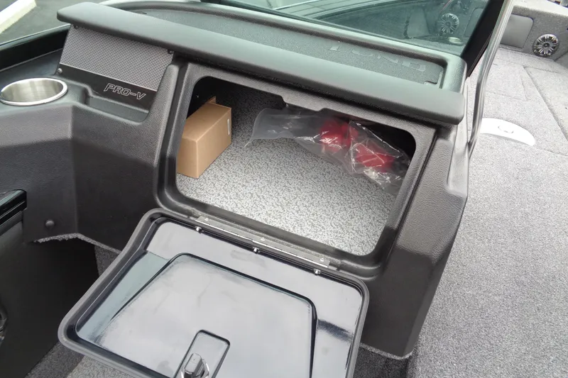 Slide: The Image of 2026 Lund 2175 Pro-V boat storage compartment with open hatch and cup holder. - 25