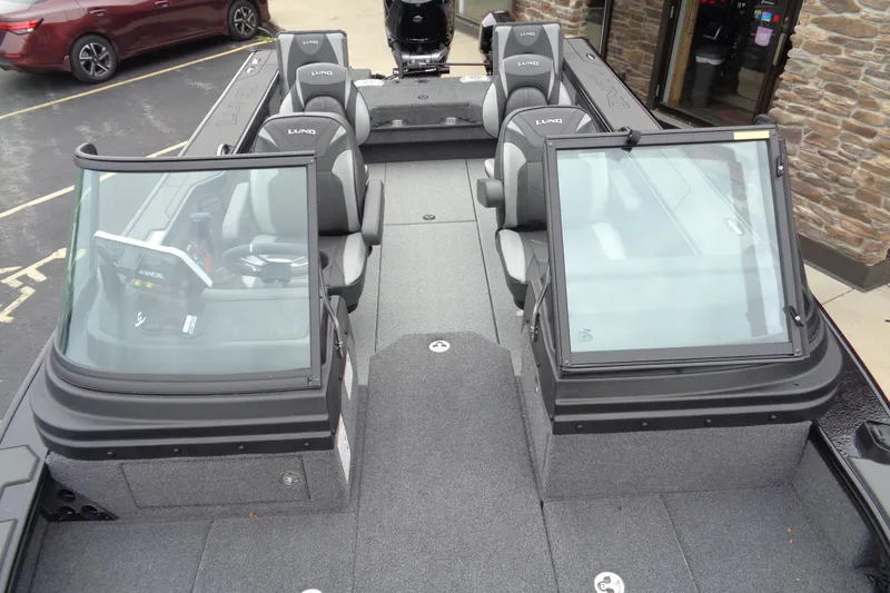 Slide: The Image of 2026 Lund 2175 Pro-V boat interior with seating and windshield, parked outdoors. - 36