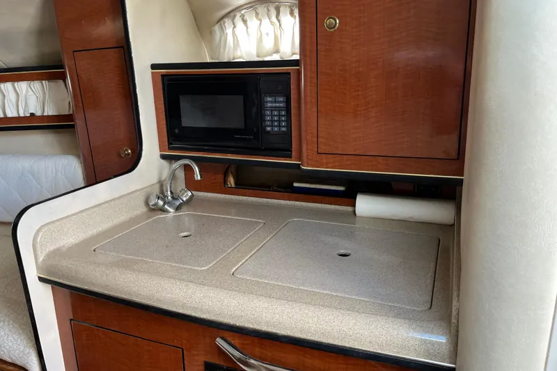 Slide: The Image of 2001 Sea Ray 280 Sundancer kitchenette with sink, microwave, and wooden cabinetry. - 5