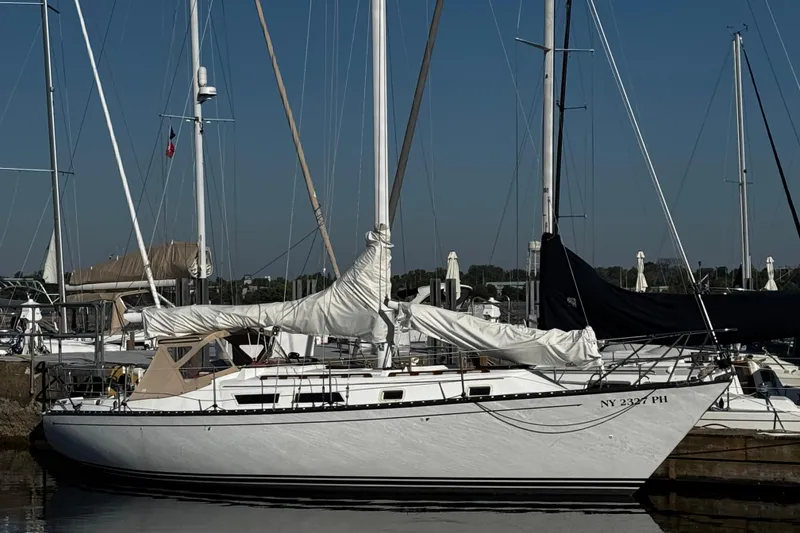 Slide: The Image of 1984 Hunter 37 Cutter sailboat docked at marina under clear blue sky. - 0