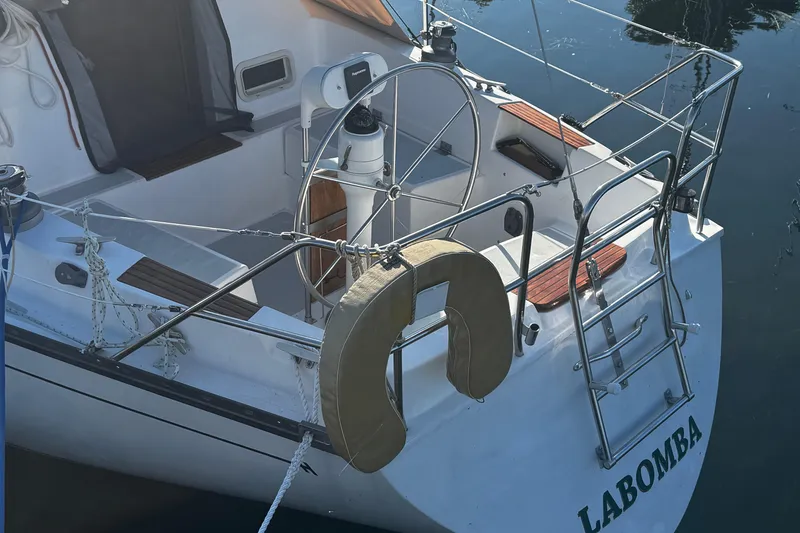 Slide: The Image of 1984 Hunter 37 Cutter sailboat with steering wheel and ladder, docked on calm water. - 4
