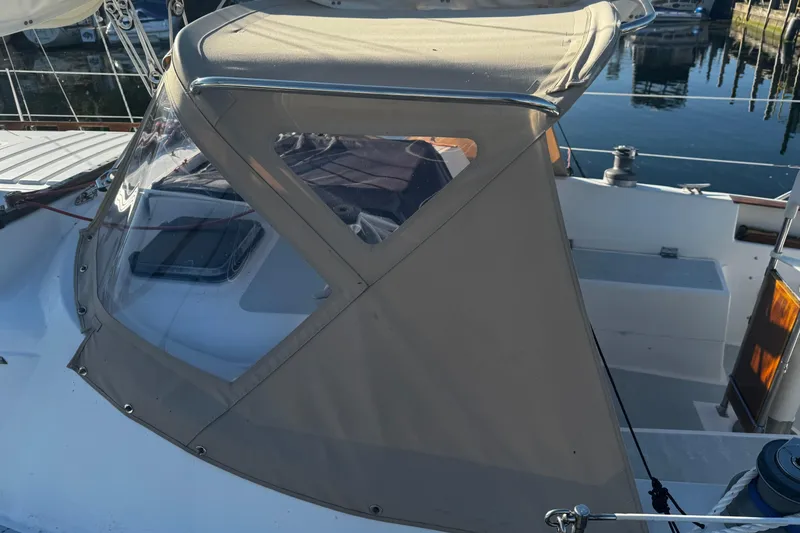 Slide: The Image of 1984 Hunter 37 Cutter sailboat with beige canopy, docked in marina. - 6