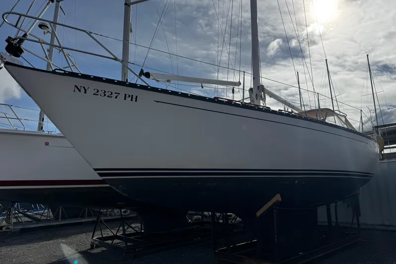 Slide: The Image of 1984 Hunter 37 Cutter sailboat on dry dock, registration NY 2327 PH, under a cloudy sky. - 34
