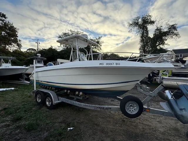 The Image of 2003 Aquasport Osprey 205 boat on trailer, parked outdoors under cloudy sky. - 0