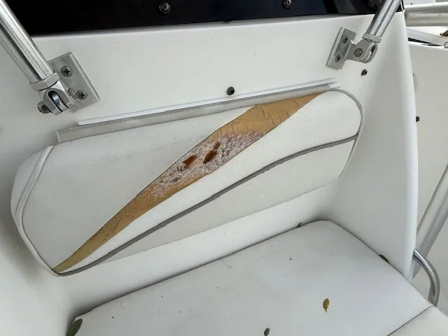 Slide: The Image of 2003 Aquasport Osprey 205 boat seat with worn upholstery and visible damage. - 12