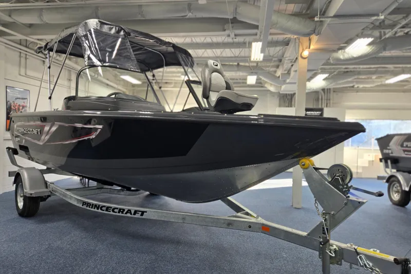 The Image of 2026 Princecraft Sport 185 boat on trailer in showroom, featuring sleek design and canopy. - 0