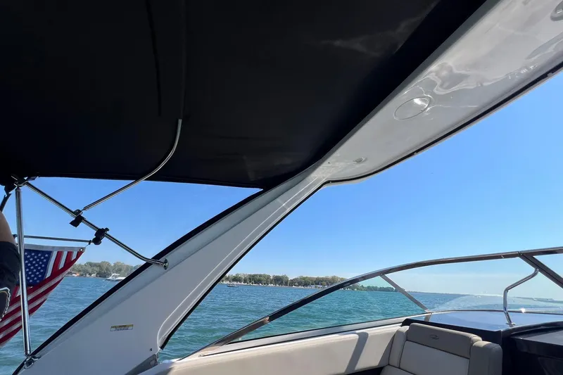 Slide: The Image of 2014 Regal 28 Express boat interior with American flag, lake view, and clear sky. - 10