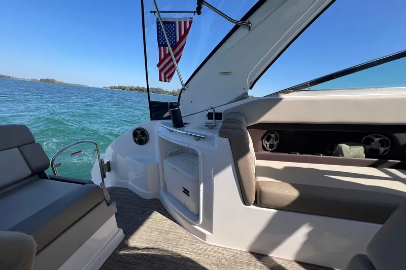 Slide: The Image of 2014 Regal 28 Express boat interior with seating, American flag, and scenic water view. - 12