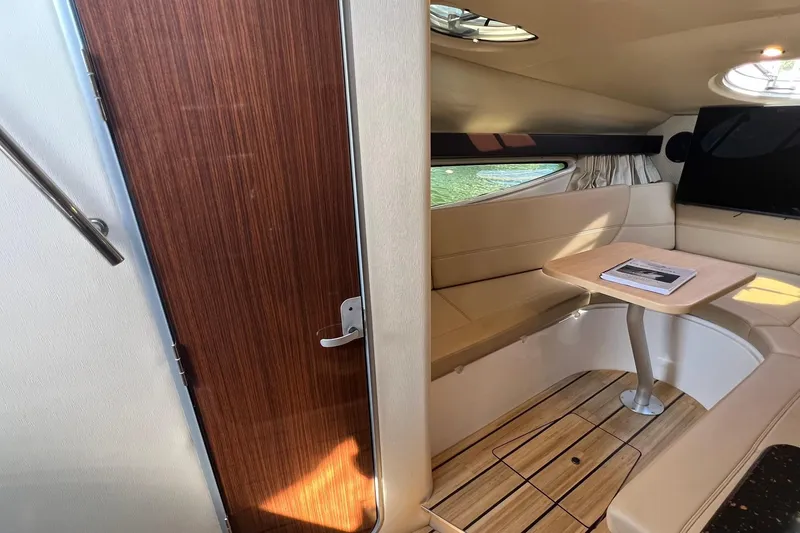 Slide: The Image of 2014 Regal 28 Express cabin interior with seating, table, and wood accents. - 14