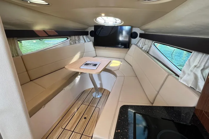 Slide: The Image of 2014 Regal 28 Express cabin interior with beige seating, table, and windows. - 17