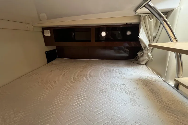 Slide: The Image of 2014 Regal 28 Express cabin interior with bed, curtains, and wooden accents. - 21