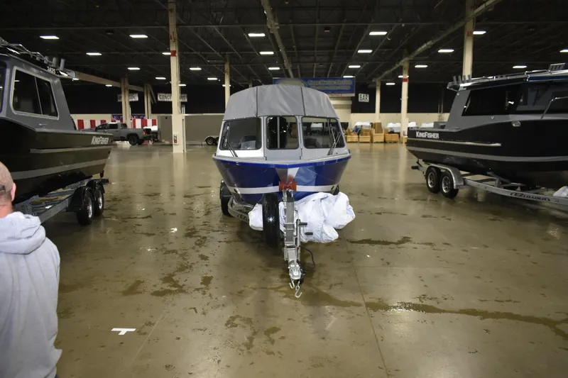 Slide: The Image of 2026 KingFisher 1825 Falcon boat displayed indoors, surrounded by other boats. - 16