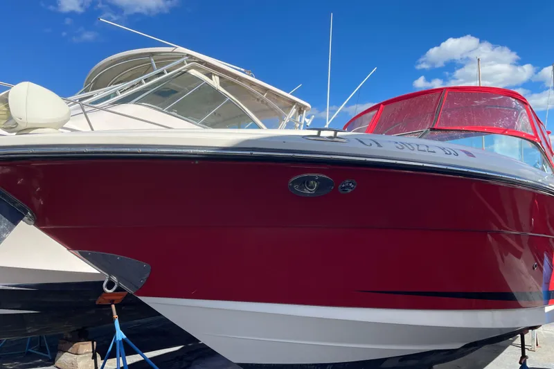 The Image of 2014 Sea Ray 270 SLX boat with red hull, docked under a clear blue sky. - 0