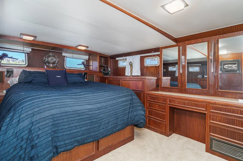 Slide: The Image of Luxurious 1979 Hatteras 58 Motor Yacht bedroom with wood paneling and blue bedding. - 58