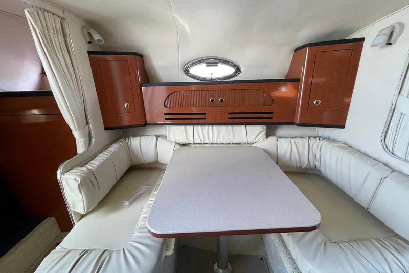 Slide: The Image of 2003 Sea Ray 280 Sundancer cabin interior with white seating and wooden cabinets. - 13