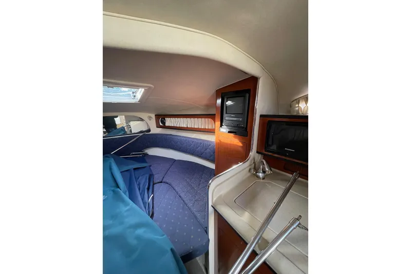 Slide: The Image of Interior of 2003 Sea Ray 280 Sundancer, featuring cozy cabin with bed, sink, and TV. - 15