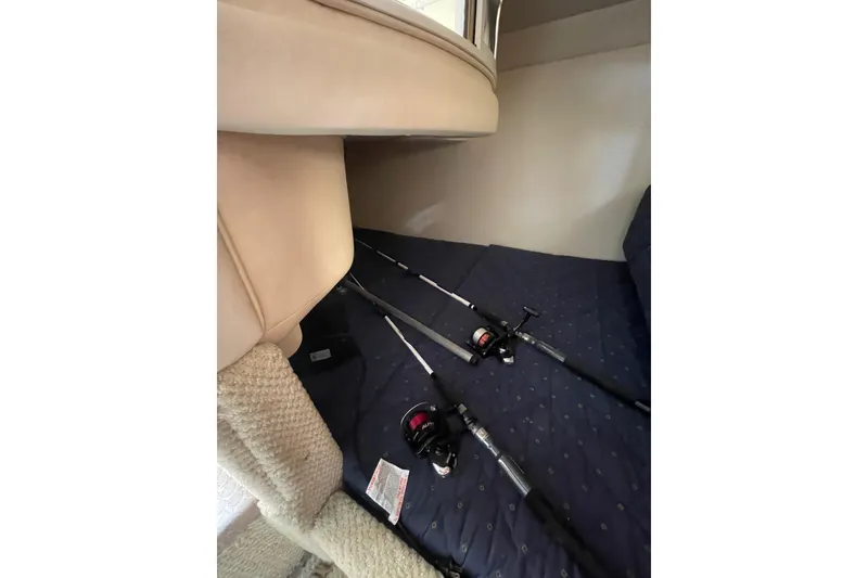 Slide: The Image of Interior of 2003 Sea Ray 280 Sundancer with fishing rods on blue upholstery. - 19